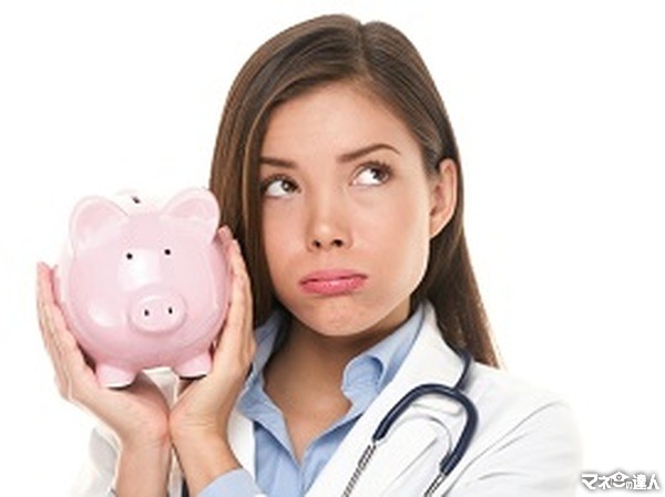 <p>Health care concept. Expensive medical insurance or medical budget cuts. Unhappy doctor woman shaking piggy ba</p>