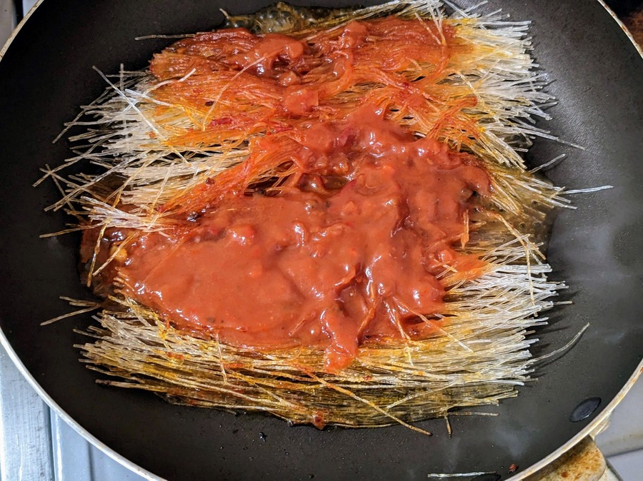 パリッとしてきたら、残りのパスタソースと水を加える