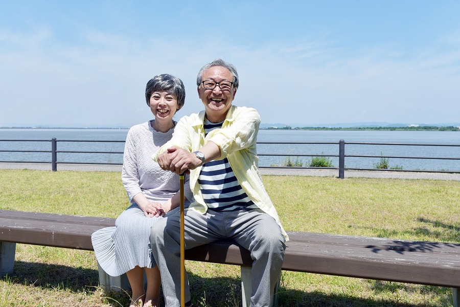 公園のベンチでほほ笑むシニア夫婦