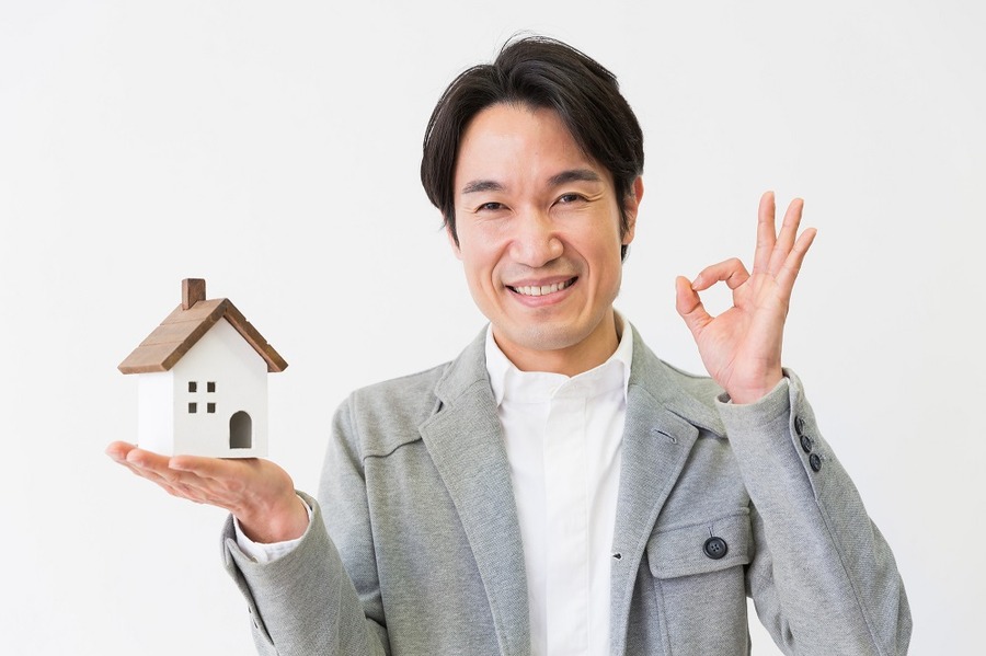家のミニチュアを持つ男性