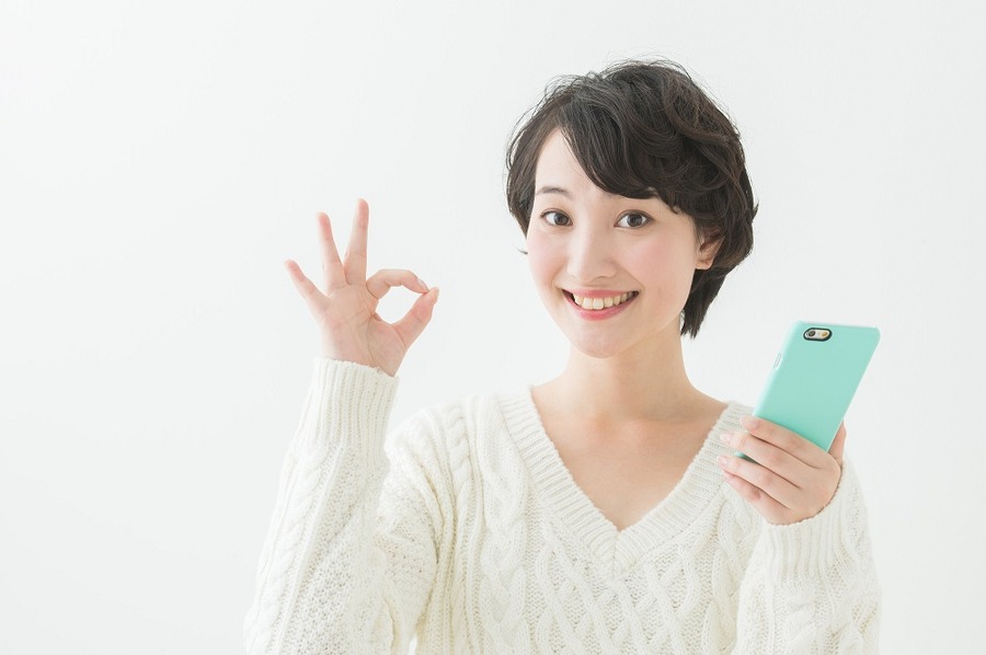 OKサインを出すスマホを持った女性
