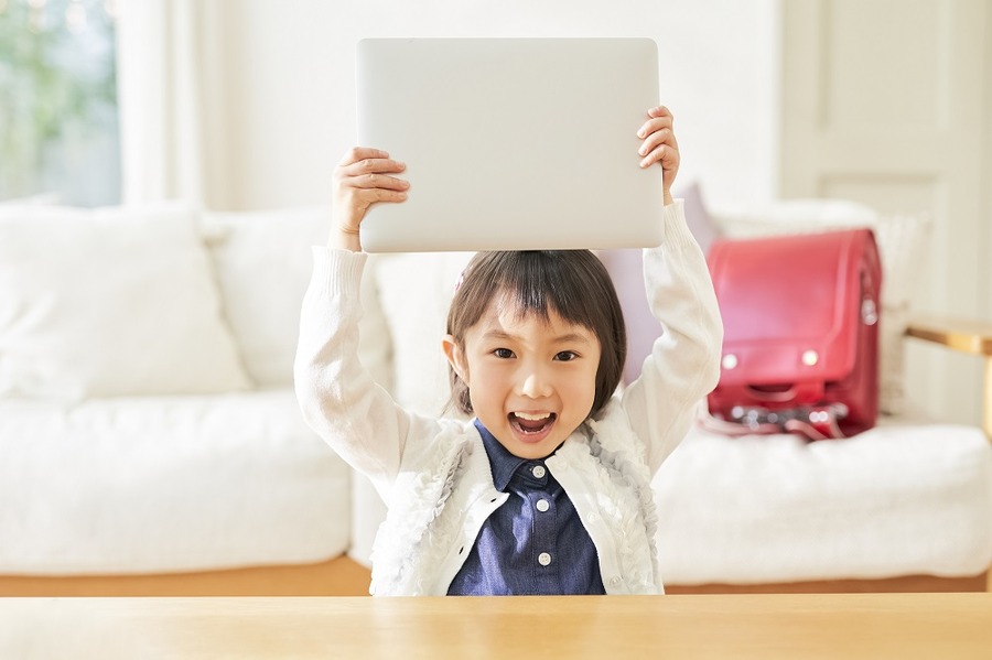 ノートPCを持って喜ぶ小学生