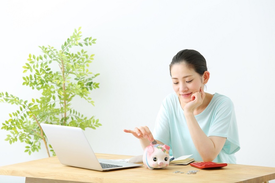豚の貯金箱にお金を入れる女性