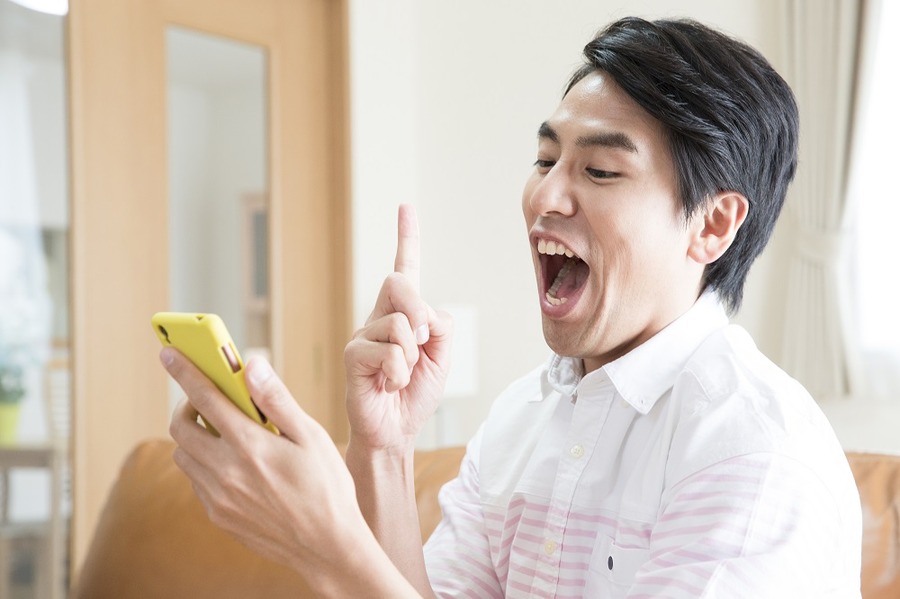 ソファに座ってスマホを見る男性