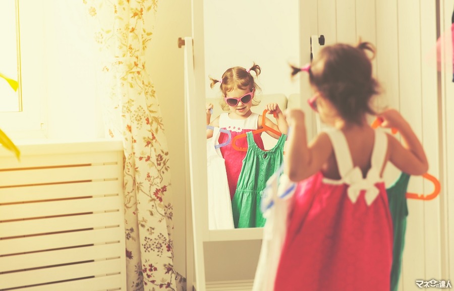 <p>little girl child looks into the mirror and choose dresses</p>