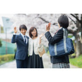 桜の下で両親に手を振る女子高生