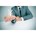 <p>a businessman sitting in a desk showing a chinese yuan or japanese yen sign in his hand</p>