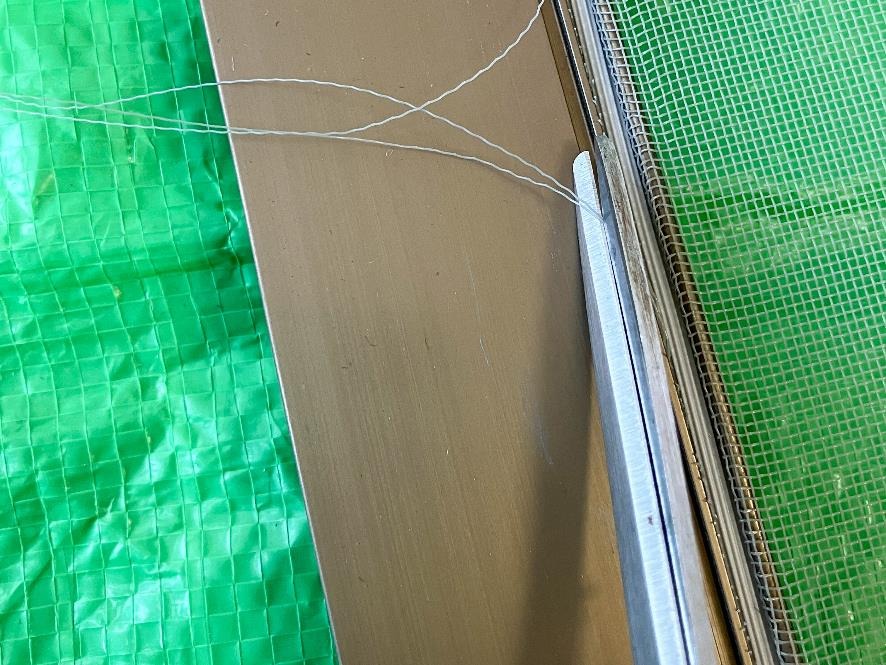 まだ枠からはみ出ている網をハサミで切り取る