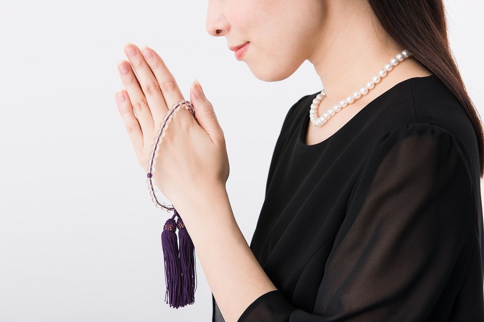 数珠をさげて祈る女性