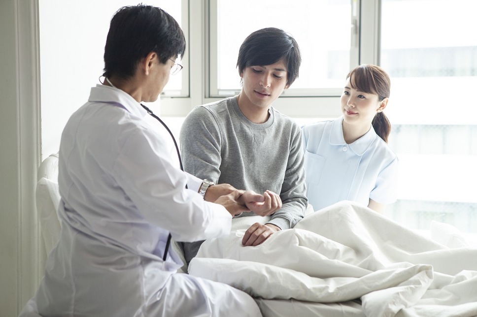 入院患者のベッドで脈拍を確認する医師