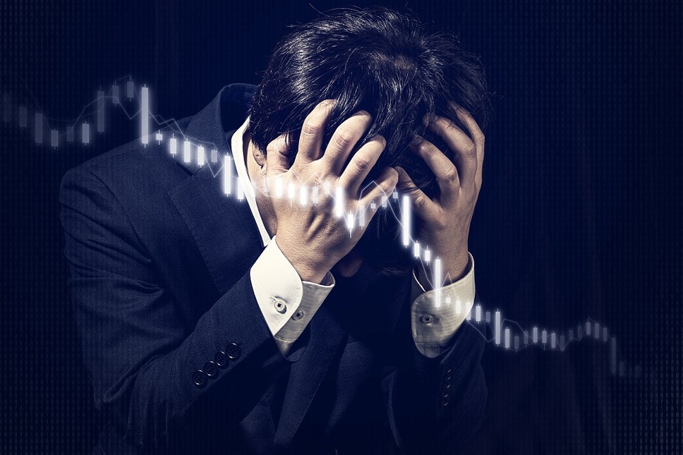 株価下落で頭を抱える男性