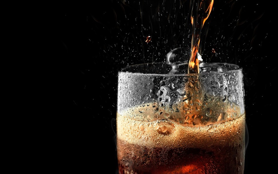 Soft drink glass with ice splash on dark background. Cola glass